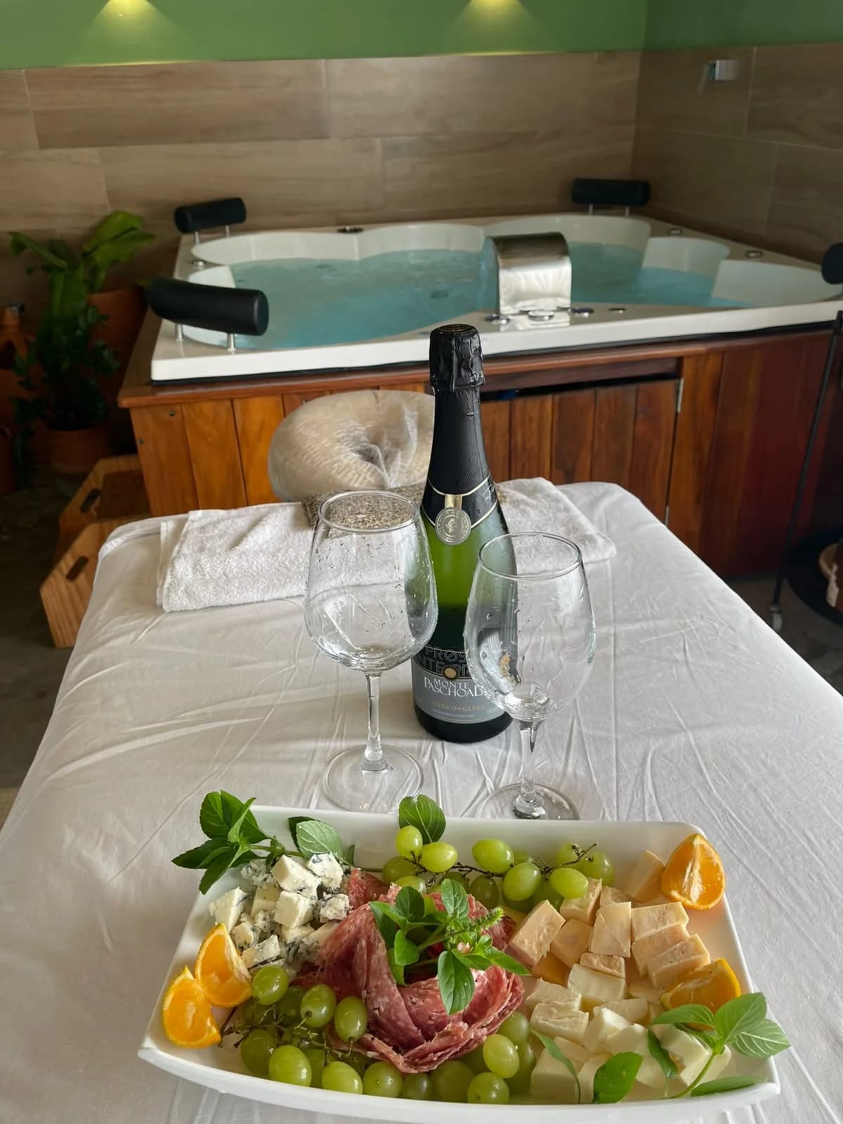 Mesa com espumante, taças e tábua de frios ao lado da jacuzzi